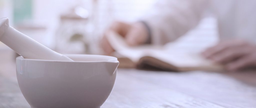 Young pharmacist holding a tablet and box of medications.