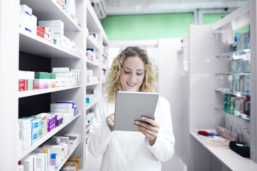 Pharmacist using tablet in pharmacy aisle