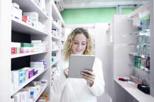 Pharmacist using tablet in pharmacy aisle