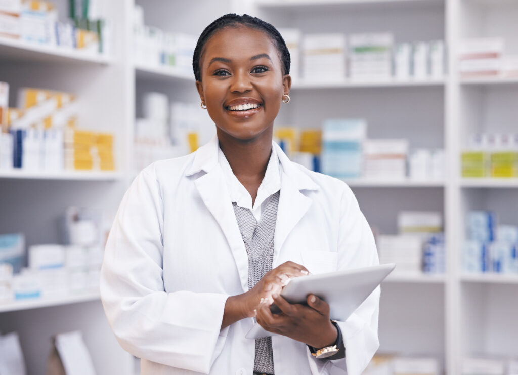 Smiling pharmacist holding tablet in pharmacy