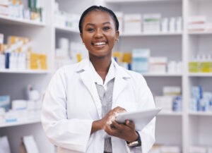 Smiling pharmacist holding tablet in pharmacy
