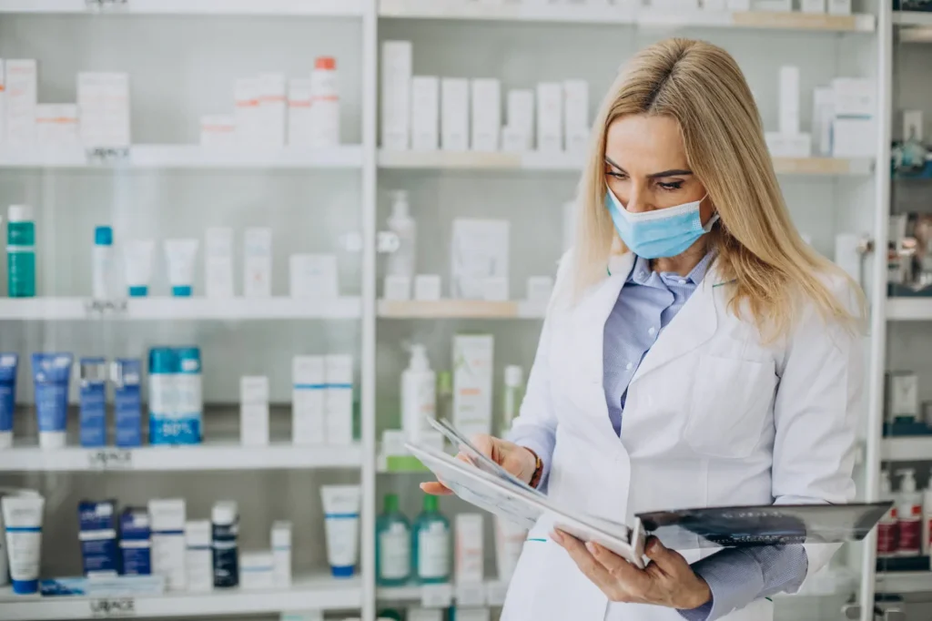Pharmacist reviewing documents in pharmacy wearing mask