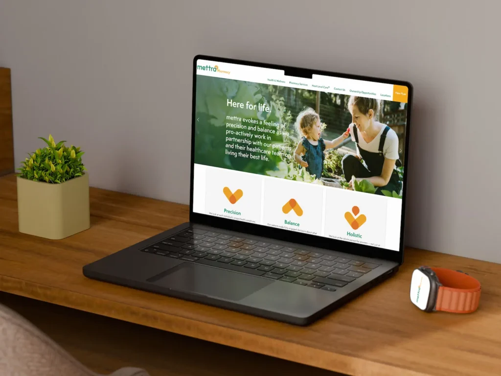 Laptop displaying mettra pharmacy website on wooden desk